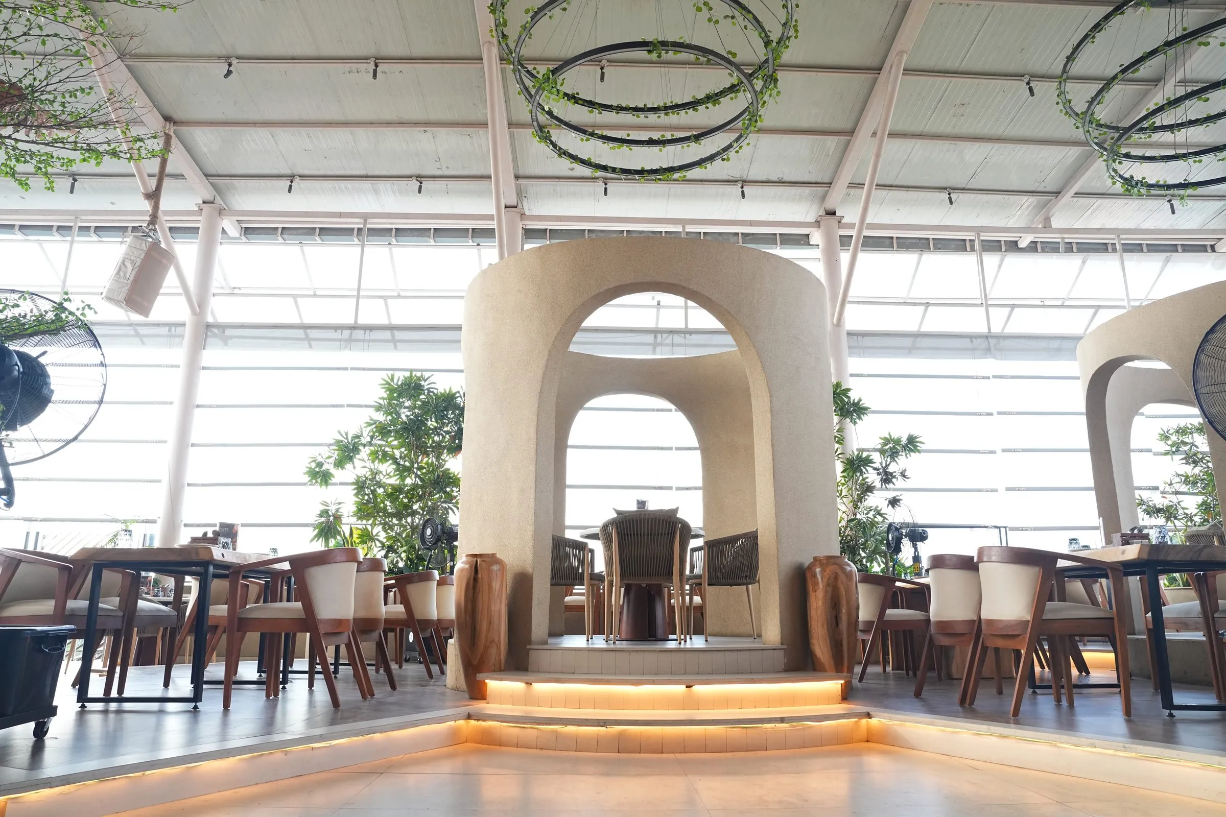A tall cream arch lit by a warm glow, with tables spread across the rooftop around it