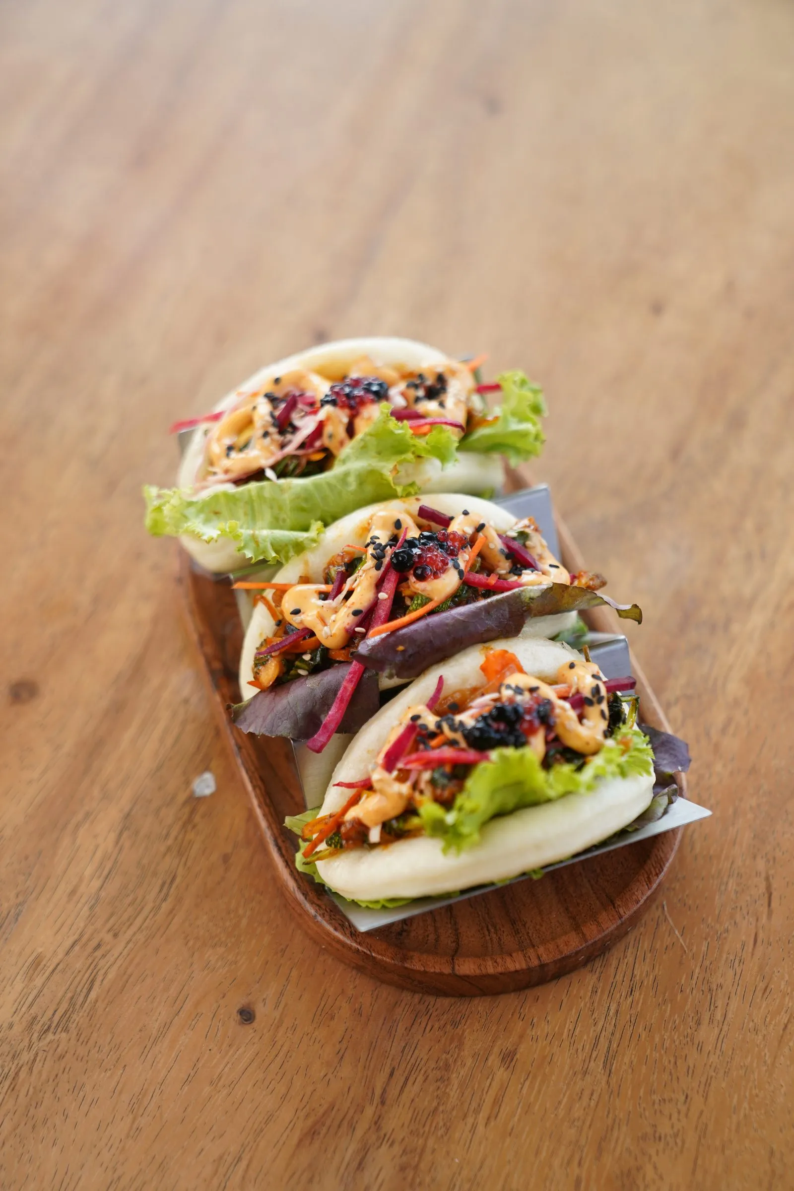 Soft bao folded around crunchy slaw and sauce, served on a wooden board