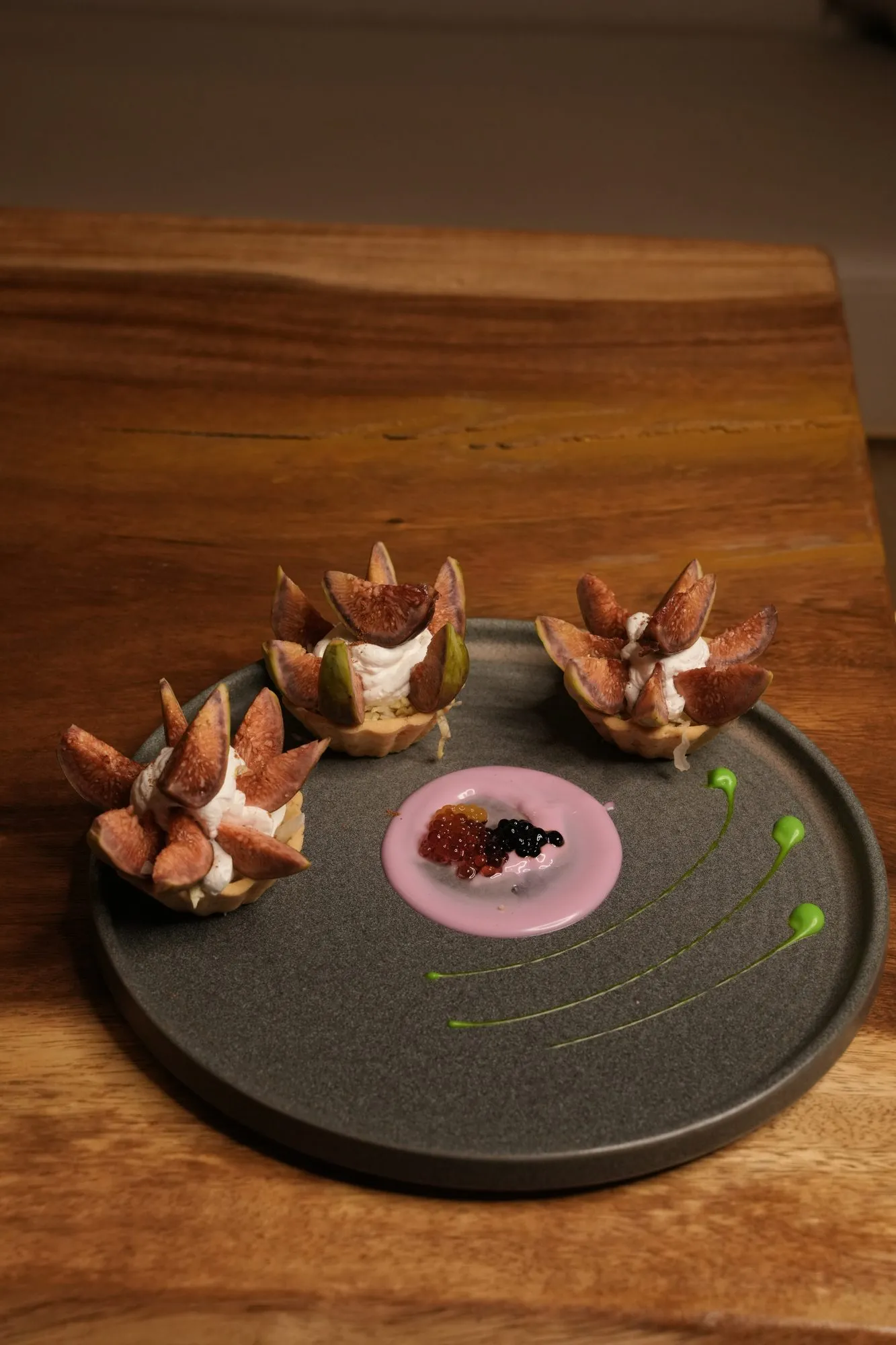 Flower-shaped bites on a dark slate plate with a beetroot dot