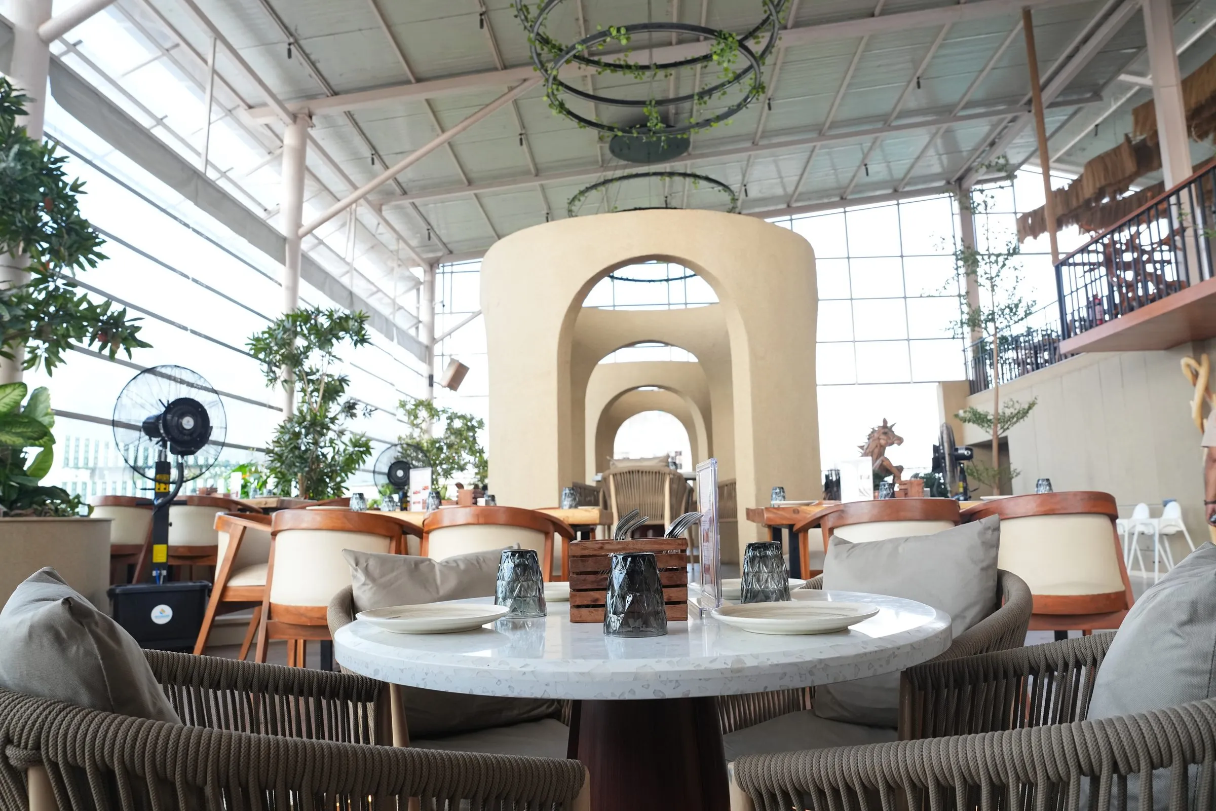 A marble table and rope chairs with layered cream arches behind