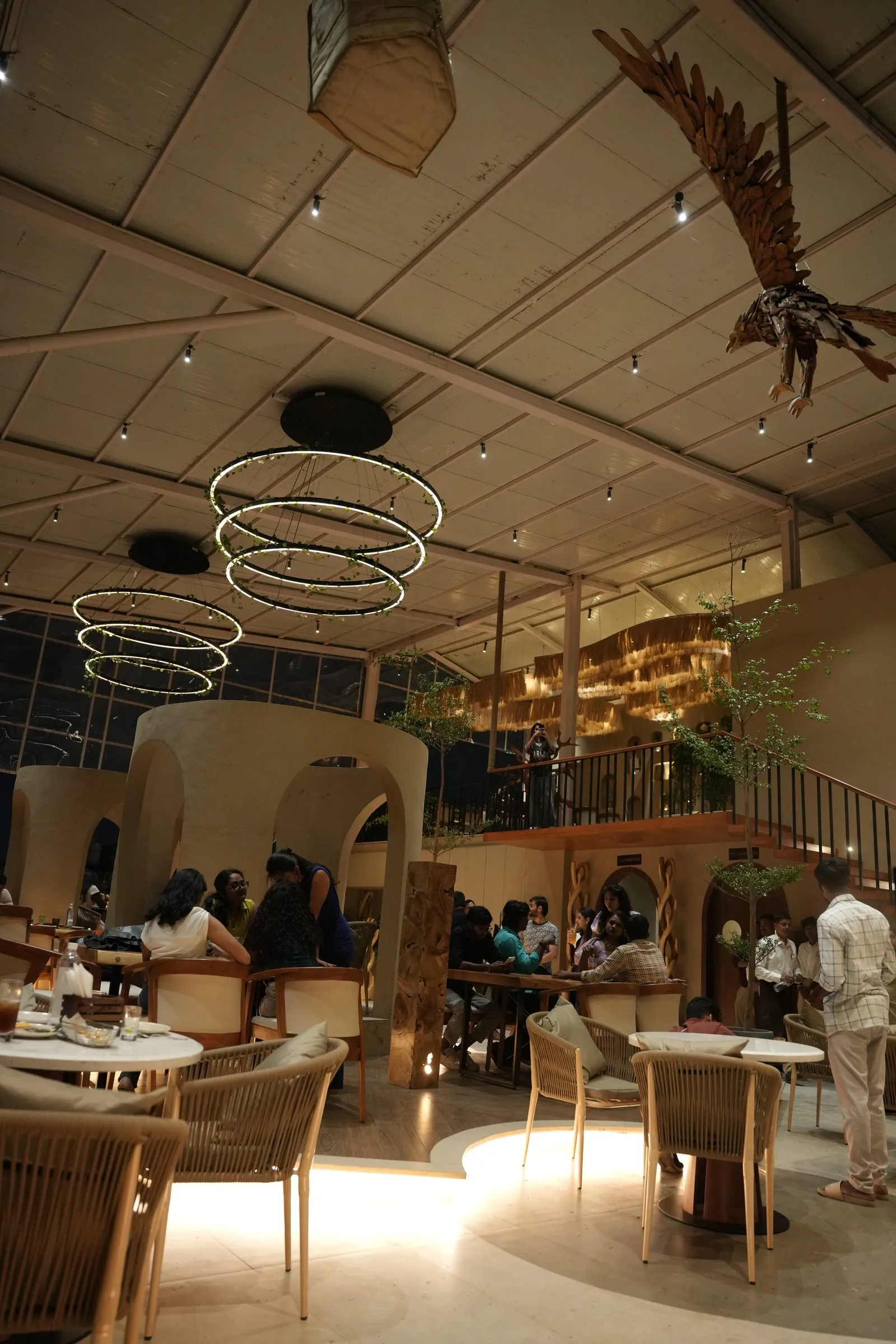 The rooftop dining room at night, warm lights and a ceiling eagle