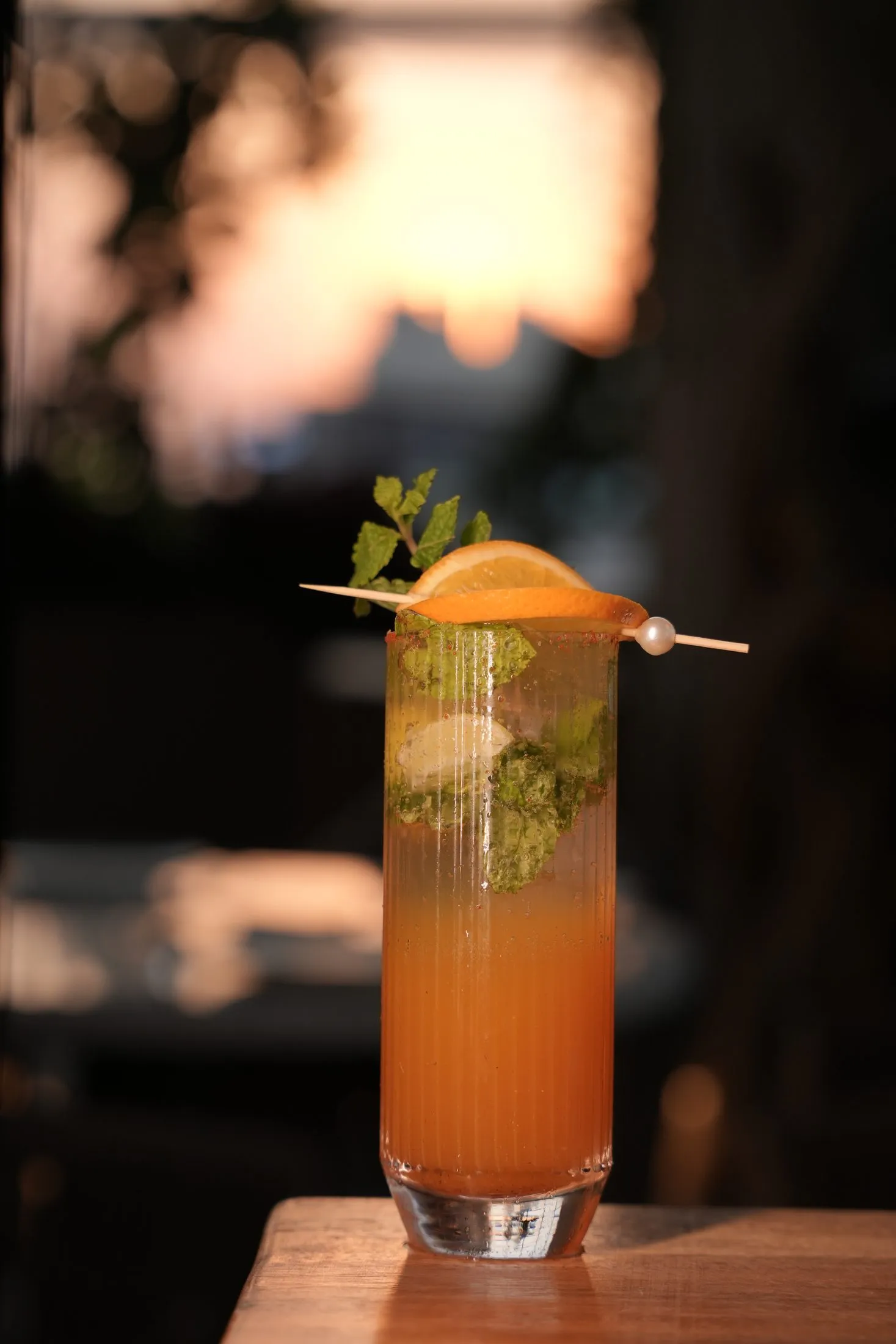 An orange mocktail garnished with a citrus wheel at dusk