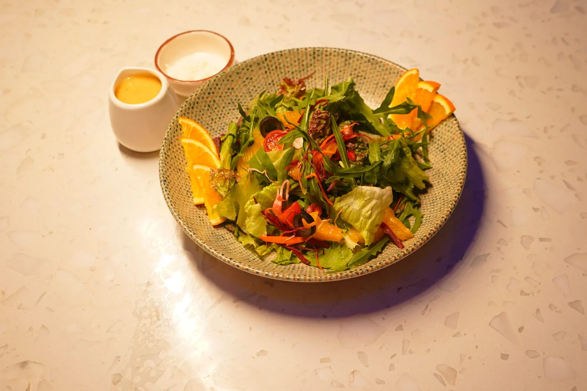 A fresh salad with orange slices and dressing in small pots