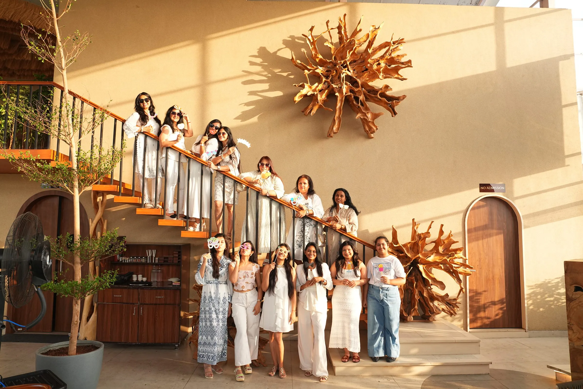 A group of guests in white and denim along the golden-lit staircase